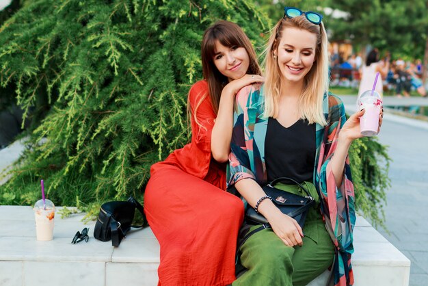 Two smiling woman talking and spending time  together in sunny modern city