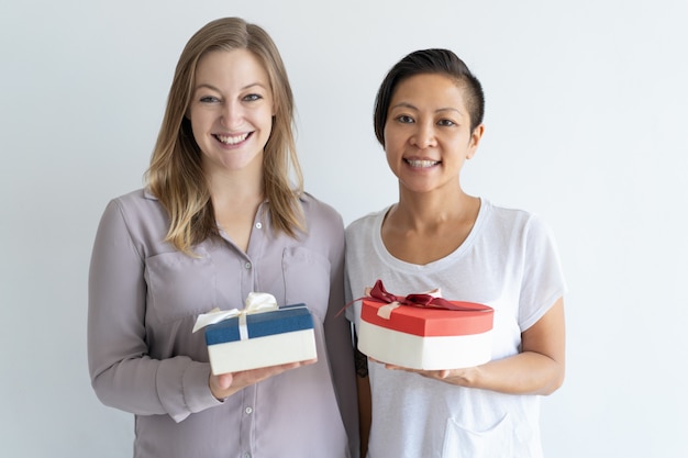 Two smiling women holding gift boxes