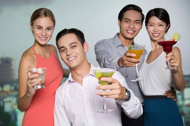 Two Smiling Young Couples Raising Glasses in Bar