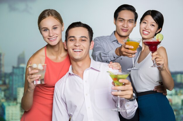 Two Smiling Young Couples with Cocktails Embracing