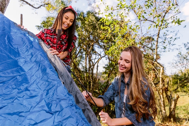 Foto gratuita due giovani donne sorridenti che impostano tenda blu