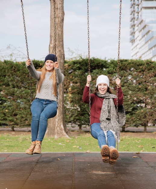 Two smiling young women on swings