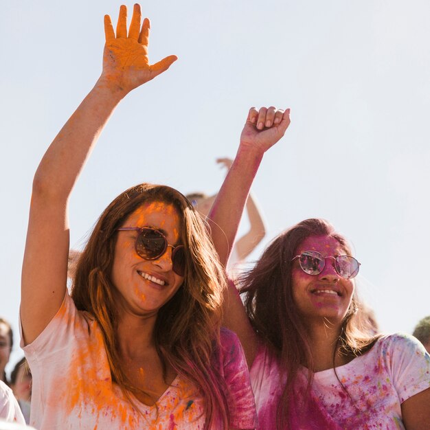 Due giovani donne sorridenti con il colore di holi sul loro viso ballare insieme