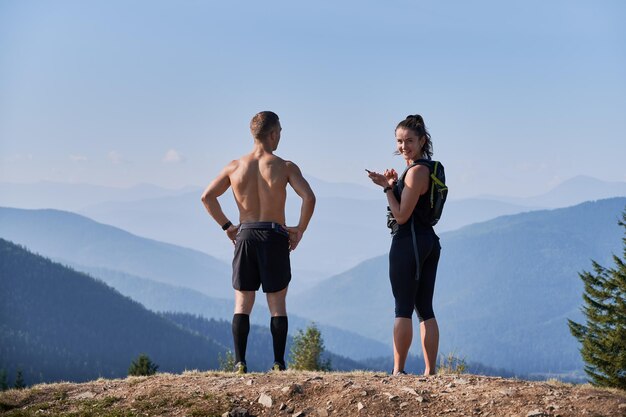 한 언덕 꼭대기에서 산 풍경을 감상하는 두 명의 스포츠 선수