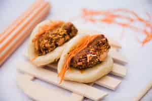 Free photo two steamed buns on wooden tray over textured backdrop