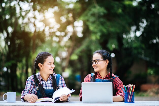 Two students studying together online with a laptop in the park