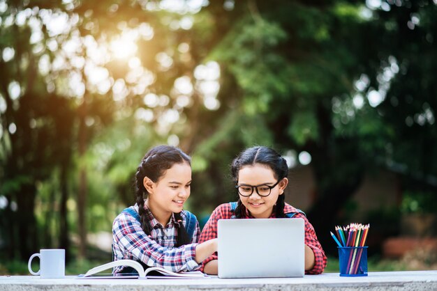 Two students studying together online with a laptop in the park