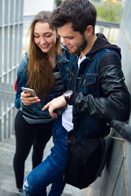 2人の学生が通りに携帯電話を使っています。