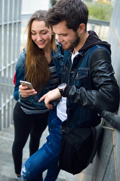 Two students using mobile phone in the street.