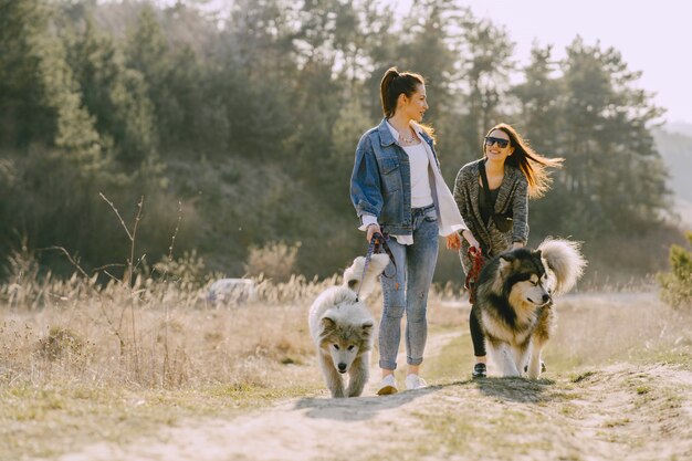 犬と日当たりの良いフィールドで2つのスタイリッシュな女の子