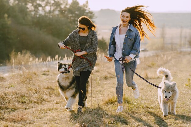 犬と日当たりの良いフィールドで2つのスタイリッシュな女の子