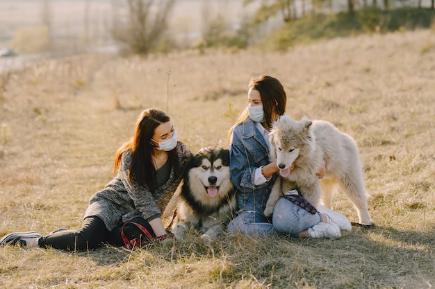 Due ragazze alla moda in un campo soleggiato con i cani