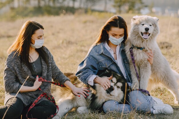 Two stylish girls in a sunny field with dogs