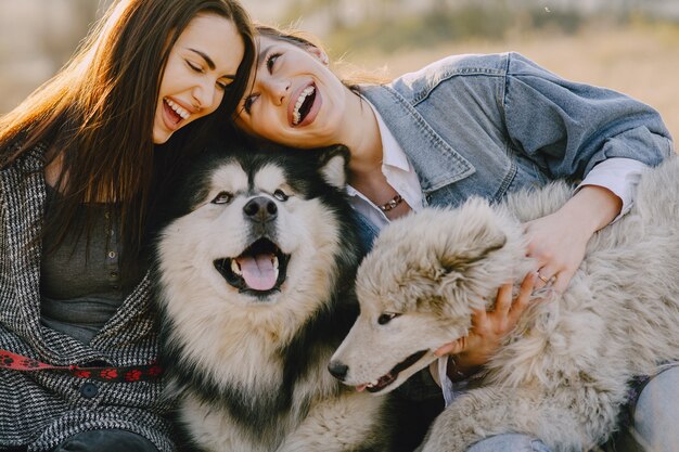 犬と日当たりの良いフィールドで2つのスタイリッシュな女の子