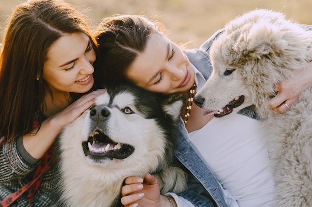 犬と日当たりの良いフィールドで2つのスタイリッシュな女の子