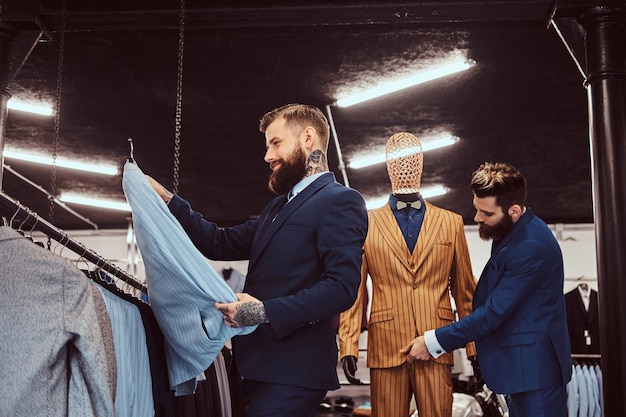 Foto gratuita due eleganti commessi vestiti elegantemente che lavorano in un negozio di abbigliamento maschile.