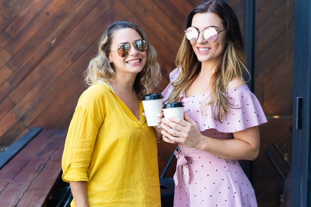 Две стильные женщины пьют кофе в кафе