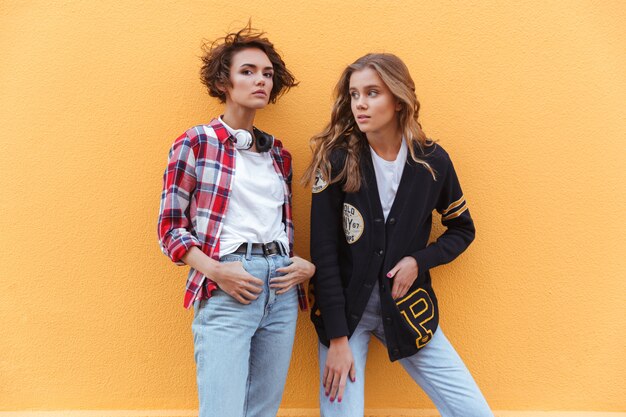 Two stylish young teenage girls posing while standing