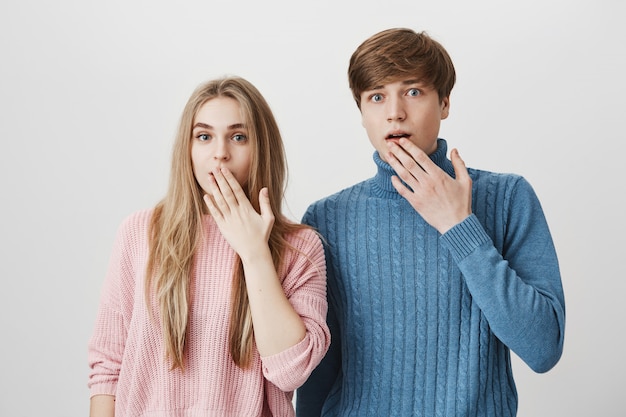 Two surprised siblings gasping. Girl and guy shocked hear gossip