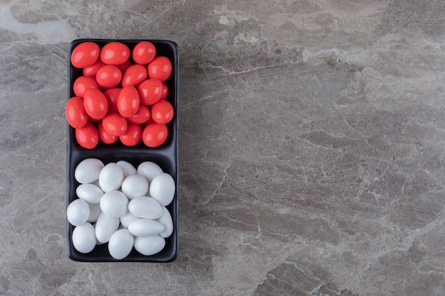 Two sweet candies in the cup on the towel on the marble surface