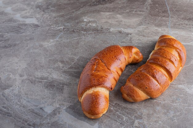 Two sweet croissants on marble table.