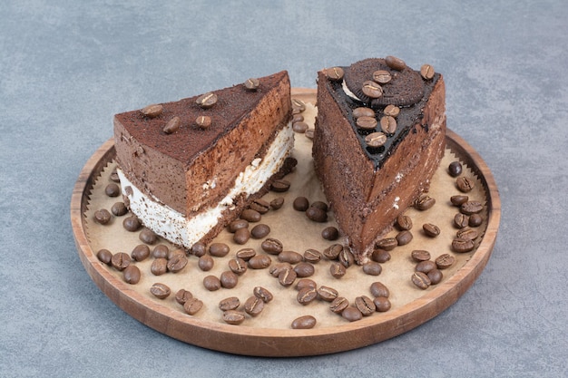 Two sweet delicious piece of cakes with coffee beans on wooden board