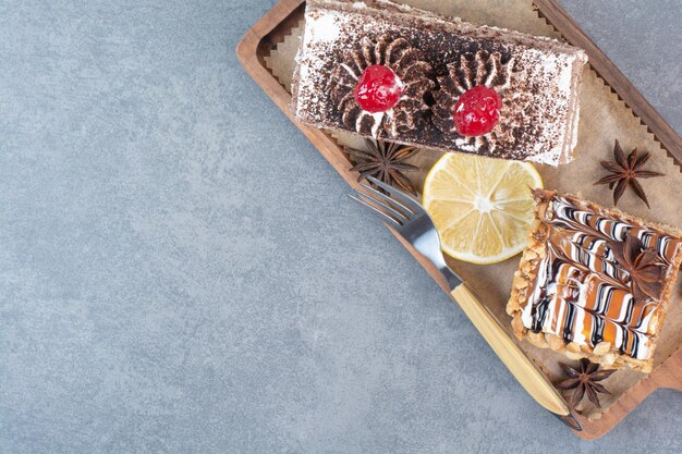 Two sweet delicious piece of cakes with star anise on wooden board