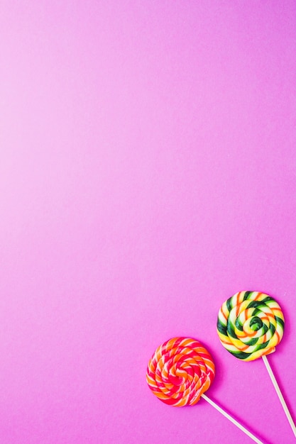 ピンクの背景に2つの甘い棒付きキャンデー