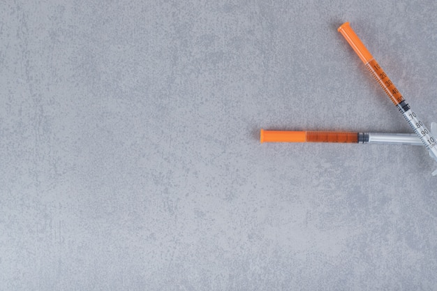 Two syringes with brown liquid on gray surface