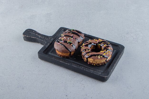 Two tasty mini chocolate cake and donut on black cutting board