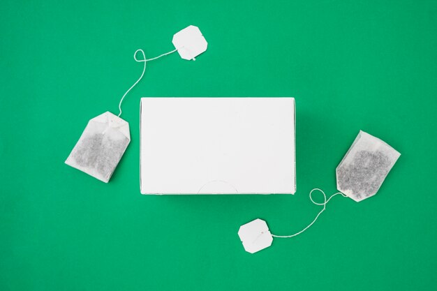 Download Premium Photo Two Tea Bags On The Side Of White Box Over The Green Background PSD Mockup Templates