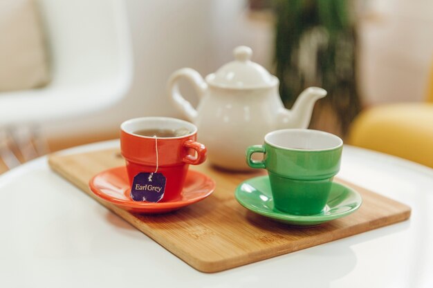 Two tea cups and tea pot on board