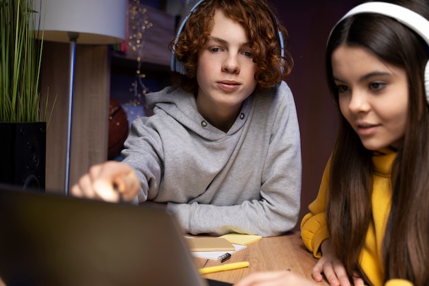 Two teenage friends playing video games together at home