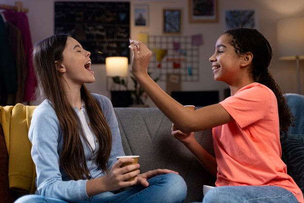 Две девочки-подростки дома пьют газировку из чашек и веселятся