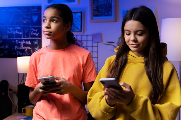 Two teenage girls texting together at home on smartphones