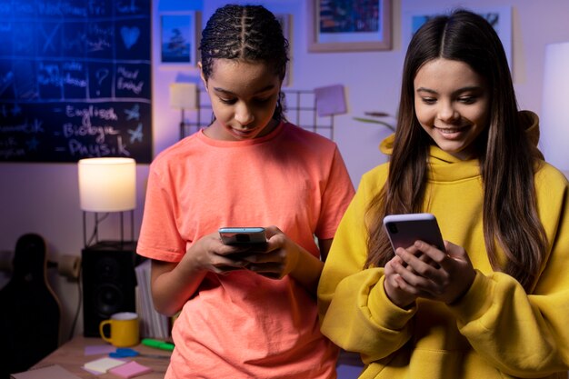 Two teenage girls texting together at home on smartphones