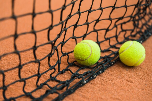 地面に黒いネットの近くに2つのテニスボール