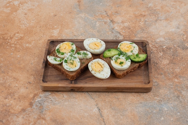 Free photo two toasts with cucumber and boiled eggs in the marble surface