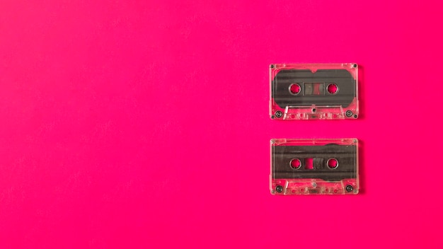 Two transparent cassette tape on pink background