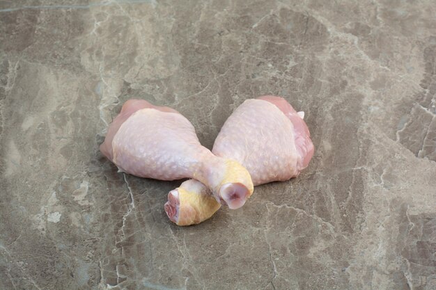 Two uncooked chicken legs on marble background. High quality photo