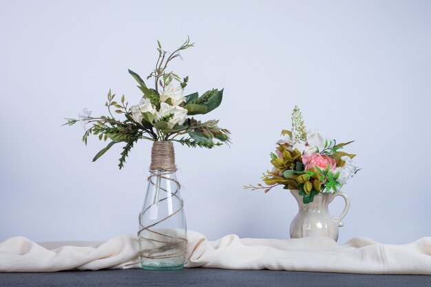 Two vases of colorful flowers on dark table.