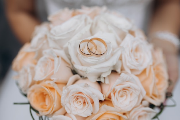 Two wedding rings lie on a wedding bouquet