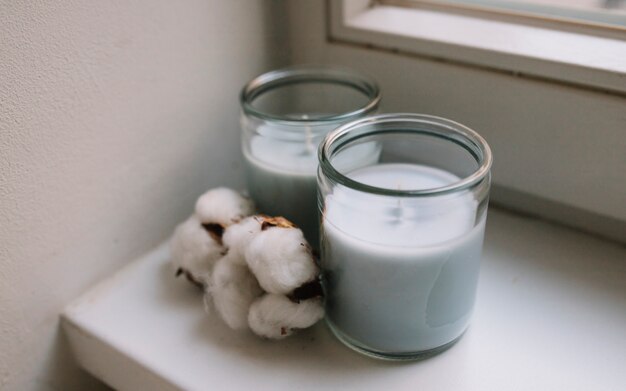 Two white candle jars with cotton pod