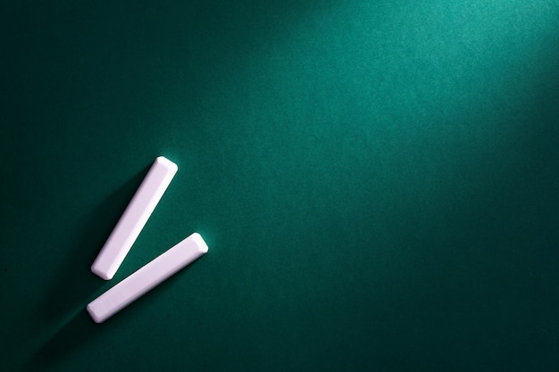 Two white chalk on blackboard