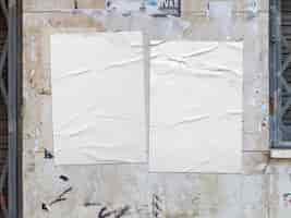 Free photo two white crumpled posters on a grunge wall