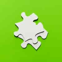 Foto gratuita un pezzo di due puzzle bianco su sfondo verde brillante