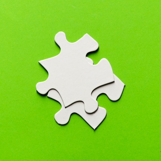밝은 녹색 배경에 두 개의 흰색 직소 퍼즐 조각