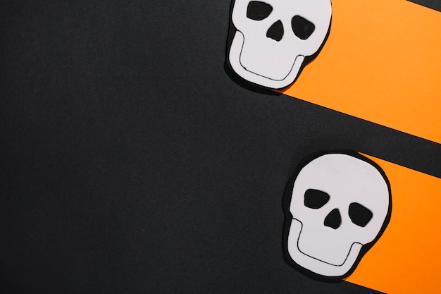 Two white skulls on orange paper