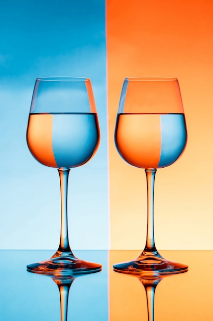 파란색과 주황색 벽 위에 물으로 두 개의 와인 잔