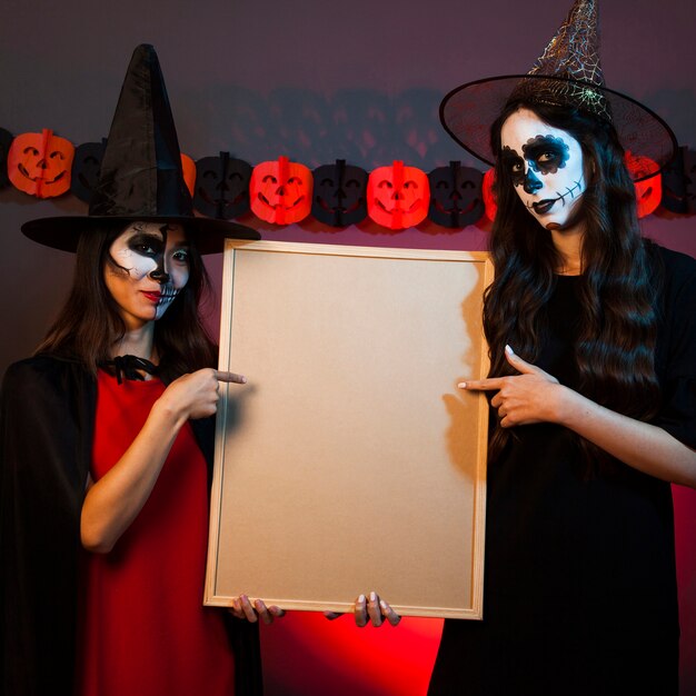 Two witches holding whiteboard